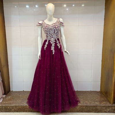 Mannequin wearing a burgundy evening ball gown with floral embellishments in sequence and beads